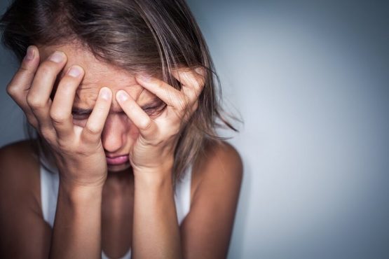 אישה טומנת את פניה בידיה ביאוש בשל דימוי עצמי נמוך