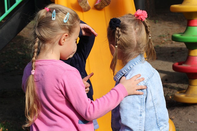 שתי ילדות מסבירות לילדה שלישית על משחק במגרש המשחקים עם המון אינטלגנציה רגשית ועדינות